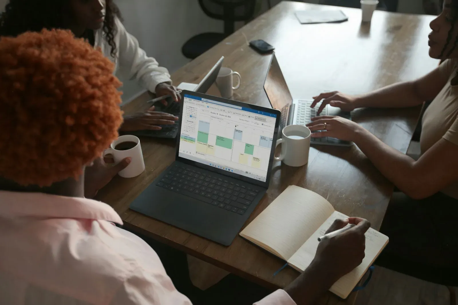Colleagues reviewing a shared schedule and taking notes around a meeting table